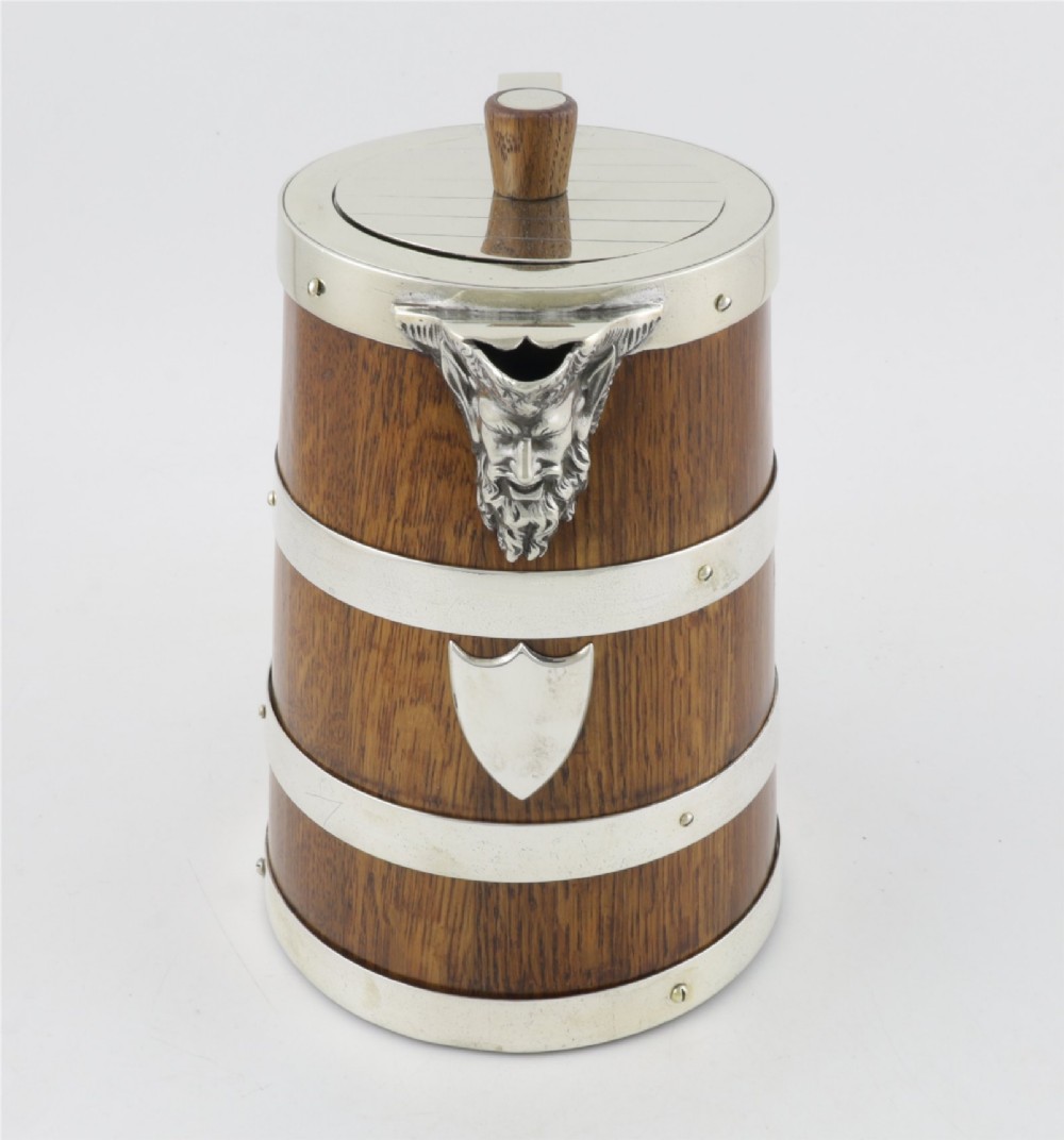 A Victorian coopered oak wine pitcher featuring silver-plated bands, a detailed Bacchus spout, and a hinged lid with a wooden finial. View XIII