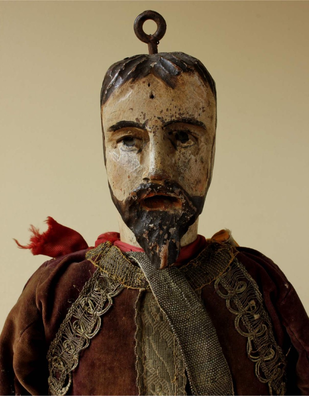 An antique French folk art marionette puppet with a hand-carved bearded wooden head, articulated limbs, and a brown velvet jacket trimmed with braid. View II