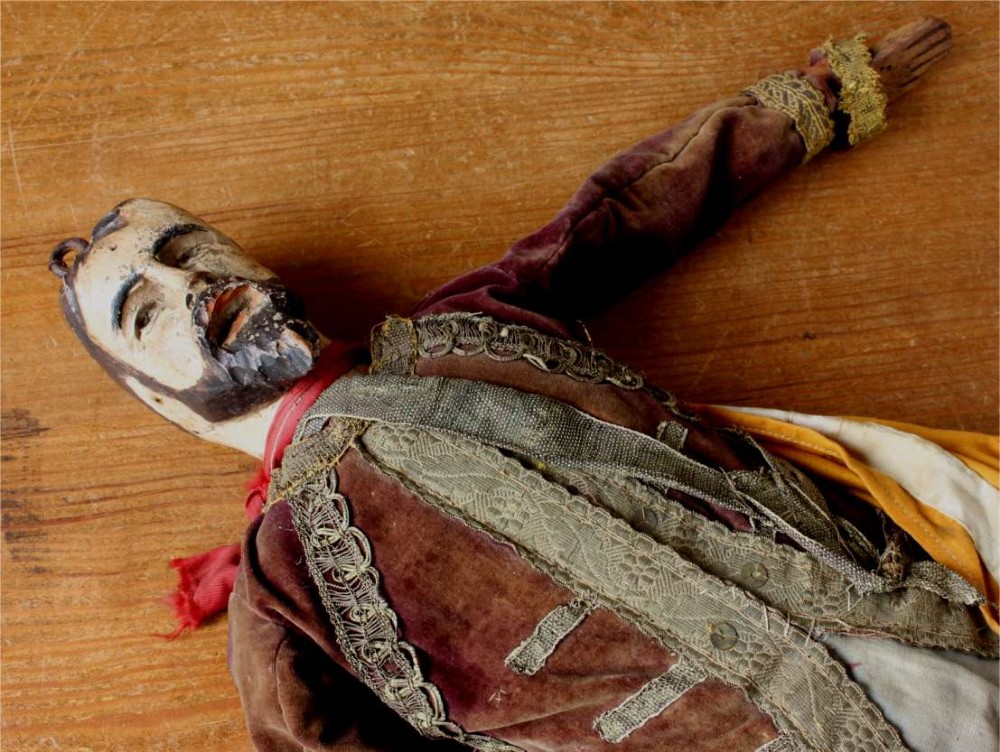 An antique French folk art marionette puppet with a hand-carved bearded wooden head, articulated limbs, and a brown velvet jacket trimmed with braid. View VI