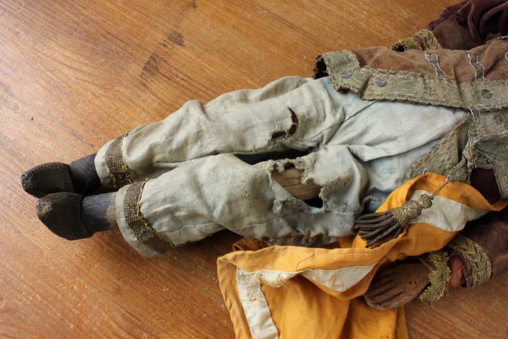 An antique French folk art marionette puppet with a hand-carved bearded wooden head, articulated limbs, and a brown velvet jacket trimmed with braid. View XII