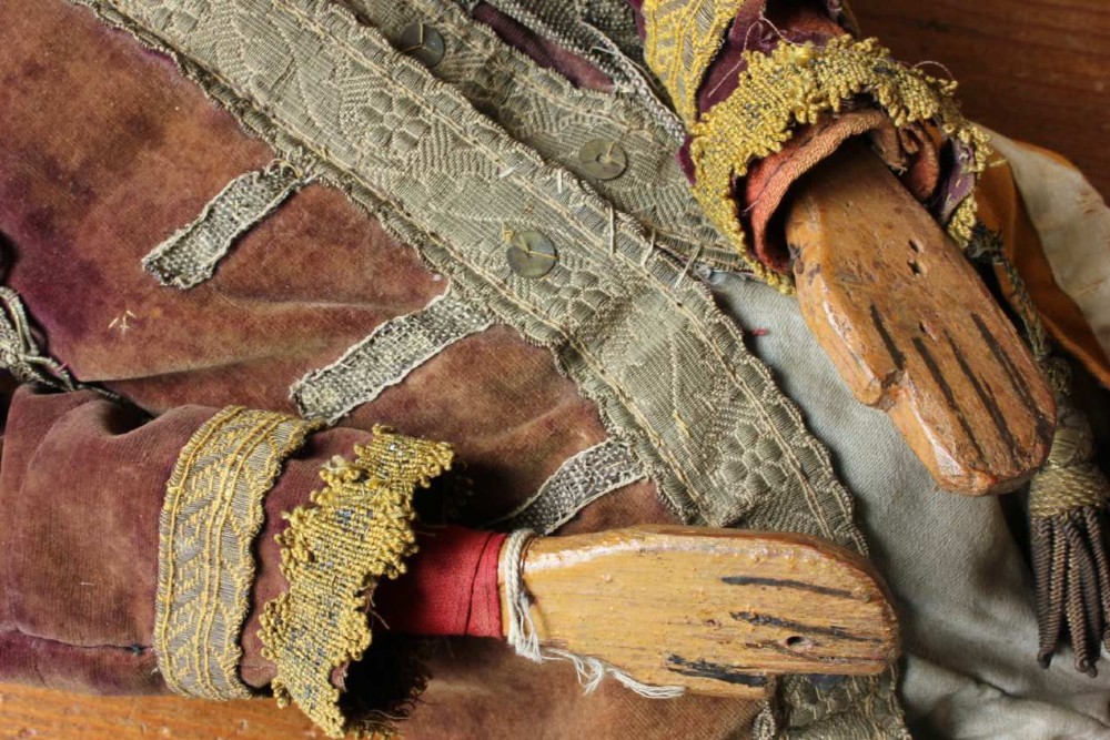 An antique French folk art marionette puppet with a hand-carved bearded wooden head, articulated limbs, and a brown velvet jacket trimmed with braid. View XV