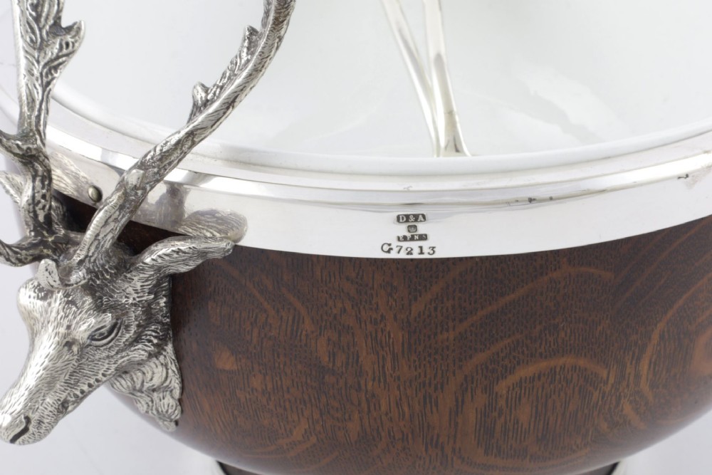 A turned dark oak bowl featuring a silver-plated rim, cast stag head handles, a central vacant silver shield, and matching serving utensils. View XI