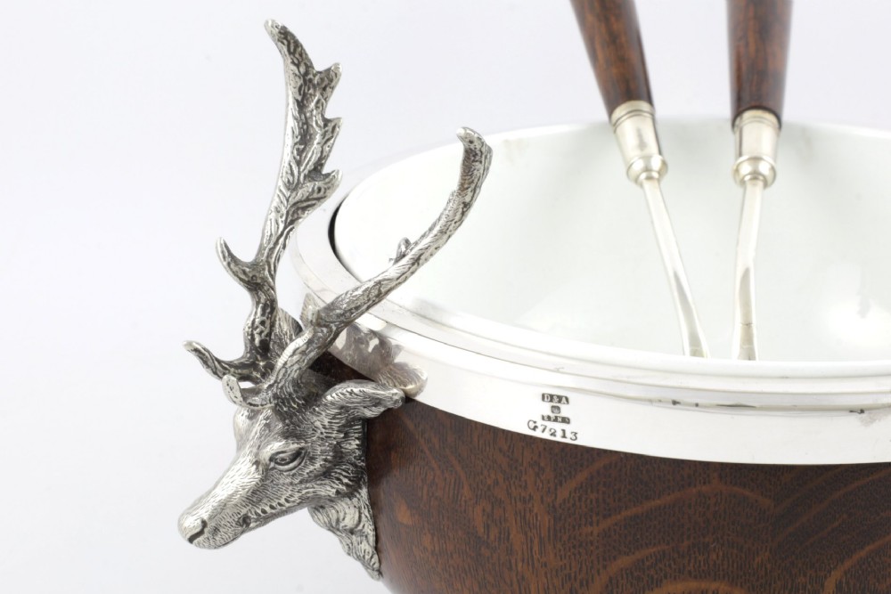 A turned dark oak bowl featuring a silver-plated rim, cast stag head handles, a central vacant silver shield, and matching serving utensils. View XIII