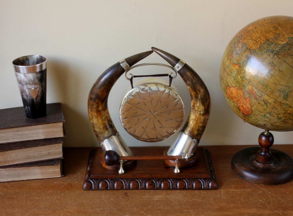 A Victorian dinner gong featuring a hammered silver-plated disc suspended between two curved bovine horns mounted on a carved oak base with a striker. View III
