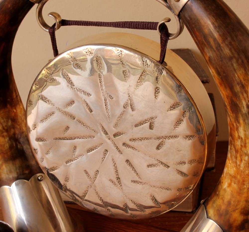 A Victorian dinner gong featuring a hammered silver-plated disc suspended between two curved bovine horns mounted on a carved oak base with a striker. View IV