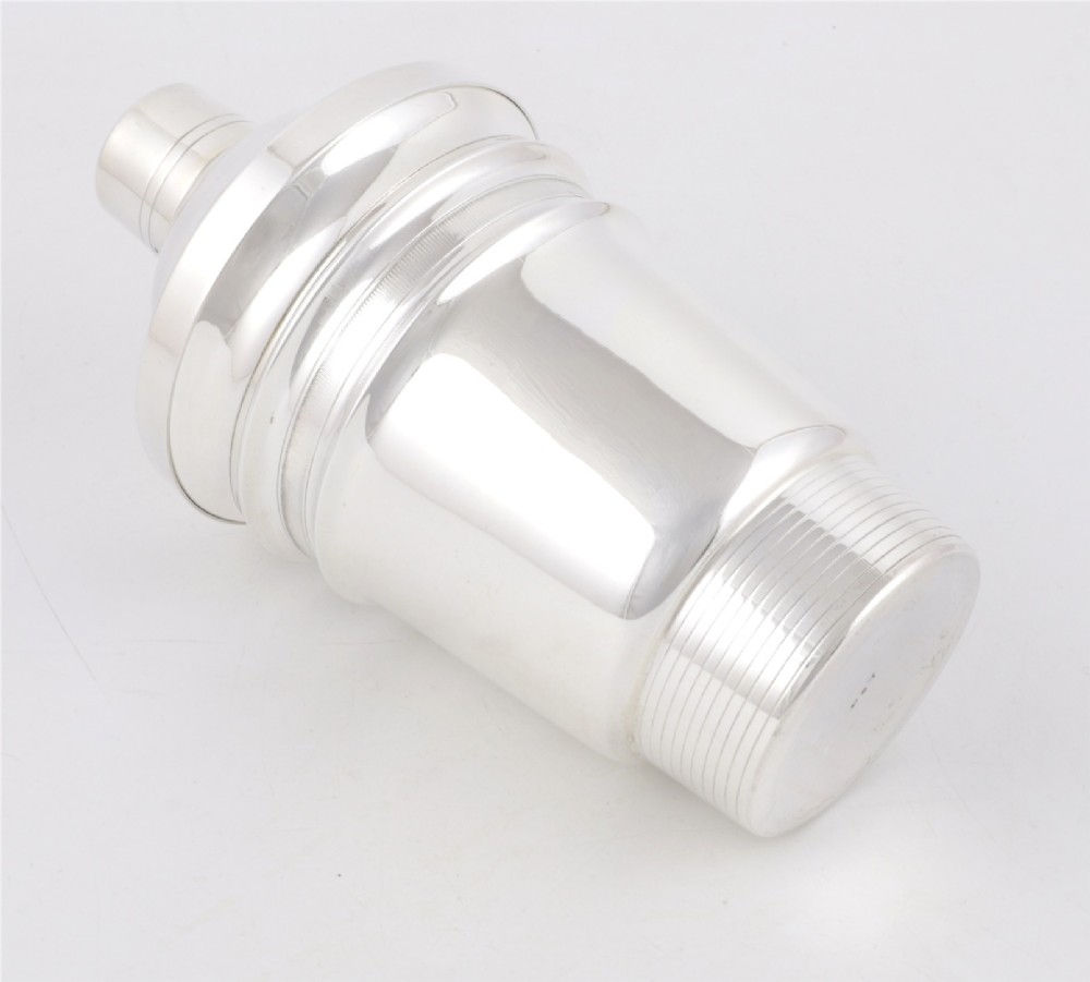 A 1930s Art Deco silver-plated cocktail shaker featuring stepped geometric contours and fine engine-turned band details. View X