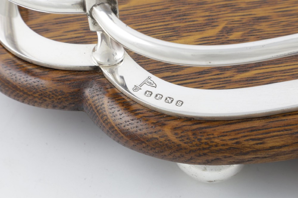 A late Victorian shaped English oak serving tray featuring a silver-plated raised gallery rail, twin wood-mounted handles, and a central blank silver cartouche. View IV