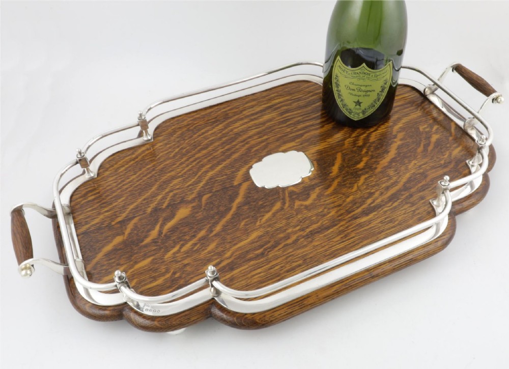 A late Victorian shaped English oak serving tray featuring a silver-plated raised gallery rail, twin wood-mounted handles, and a central blank silver cartouche. View VII