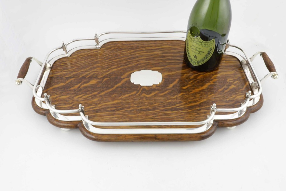 A late Victorian shaped English oak serving tray featuring a silver-plated raised gallery rail, twin wood-mounted handles, and a central blank silver cartouche. View VIII