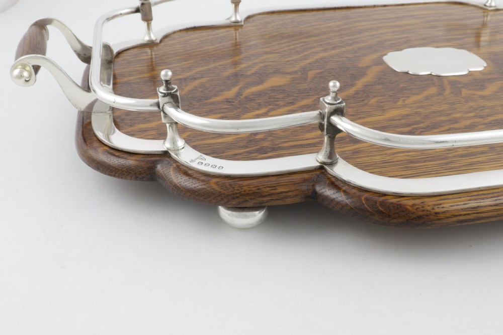 A late Victorian shaped English oak serving tray featuring a silver-plated raised gallery rail, twin wood-mounted handles, and a central blank silver cartouche. View IX