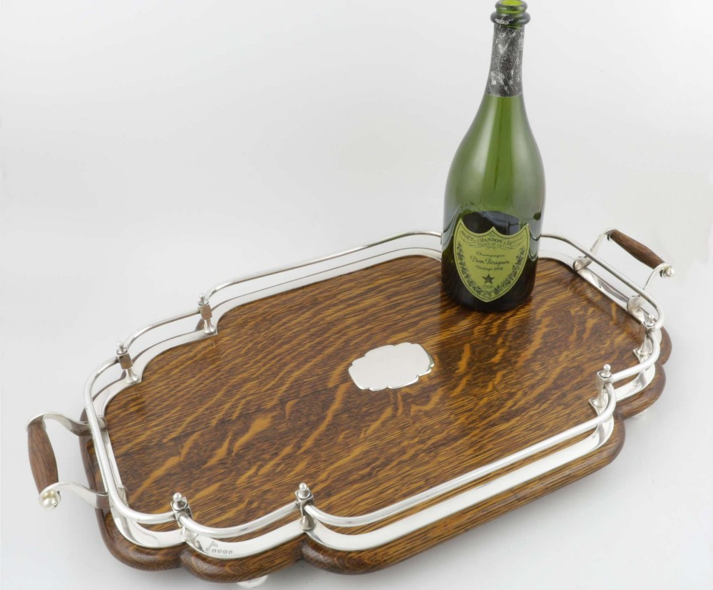 A late Victorian shaped English oak serving tray featuring a silver-plated raised gallery rail, twin wood-mounted handles, and a central blank silver cartouche. View XI