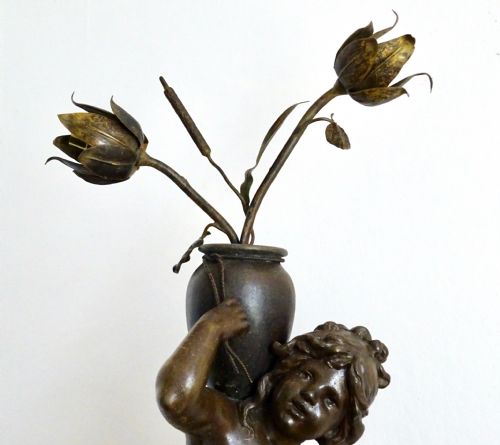 fig 2. A bronzed spelter table lamp featuring a sculpted cherub figure holding a urn, with floral stem lights mounted on a round marble base.