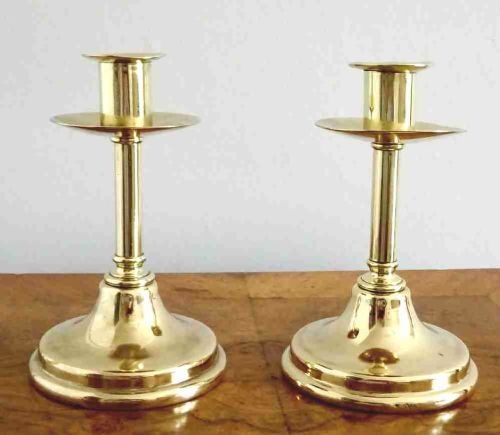 fig 1. A pair of polished late Victorian brass candlesticks featuring turned column stems, wide drip pans, and flared circular bases.