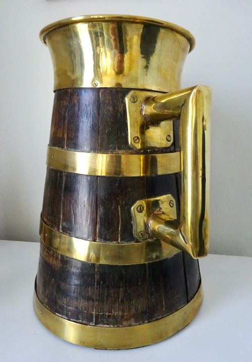 fig 1. A Victorian coopered oak jug constructed from dark wooden staves with polished brass binding bands, rim, and handle.