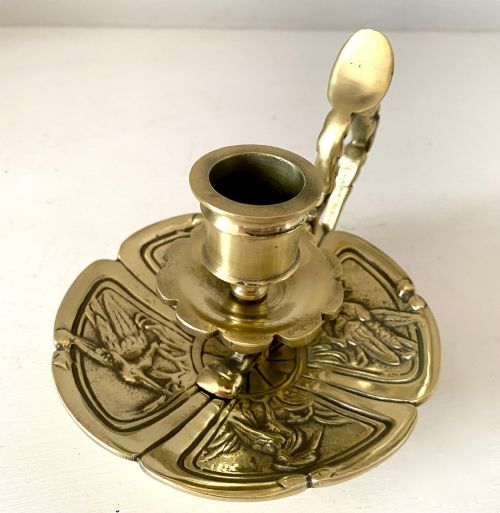 fig 1. An antique French brass chamberstick featuring a scalloped tray base, turned candle socket, and a cast handle shaped like a grotesque face.
