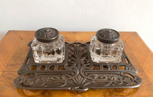 fig 1. An Art Nouveau dark metal double inkstand featuring pierced floral scrollwork and two square glass inkwells with embossed metal lids.