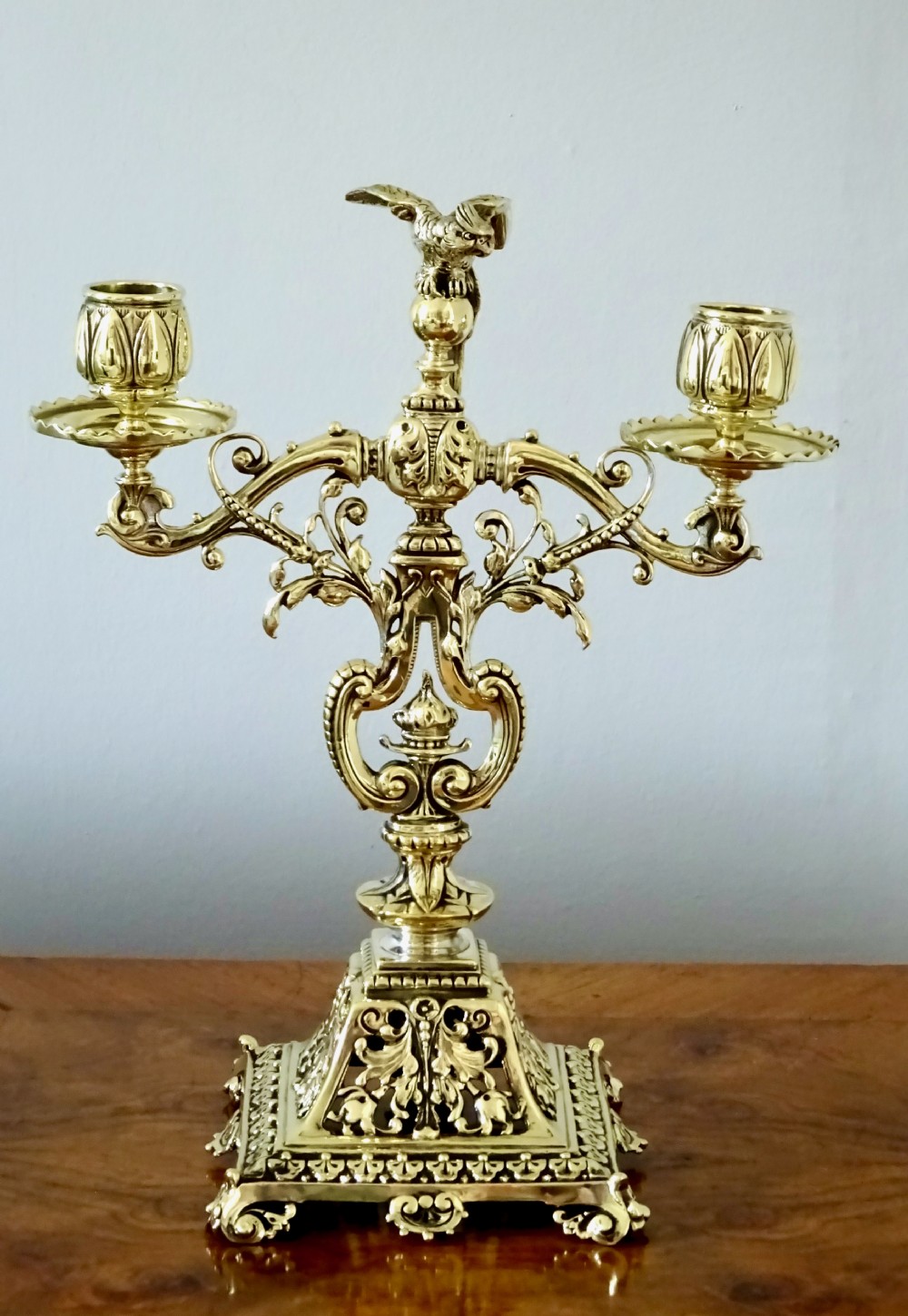 1887 - A BRASS CANDELABRA WITH A PARROT ON THE TOP