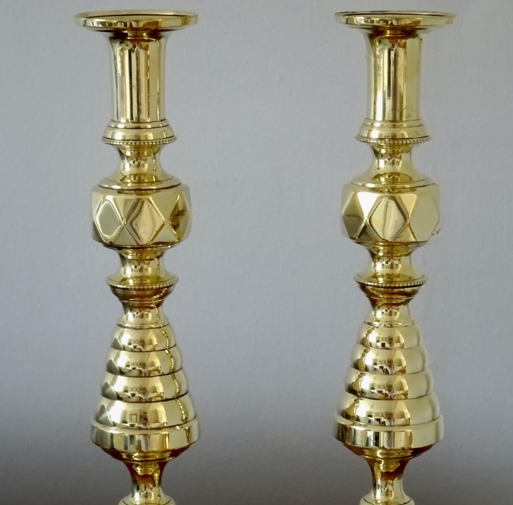 A pair of tall turned brass candlesticks featuring beehive stems, diamond knops, and square bases with canted corners. View II