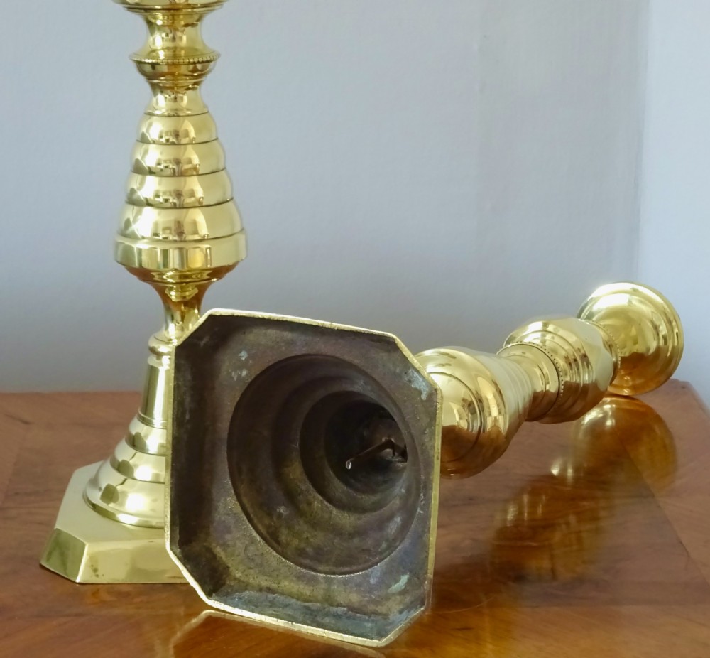 A pair of tall turned brass candlesticks featuring beehive stems, diamond knops, and square bases with canted corners. View V
