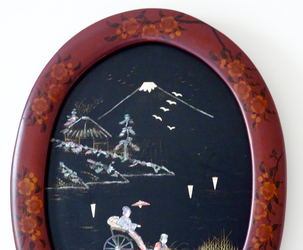 An oval red-lacquered framed artwork depicting a Japanese scene with Mount Fuji and a rickshaw in mother-of-pearl and abalone shell inlay against a black background. View IV
