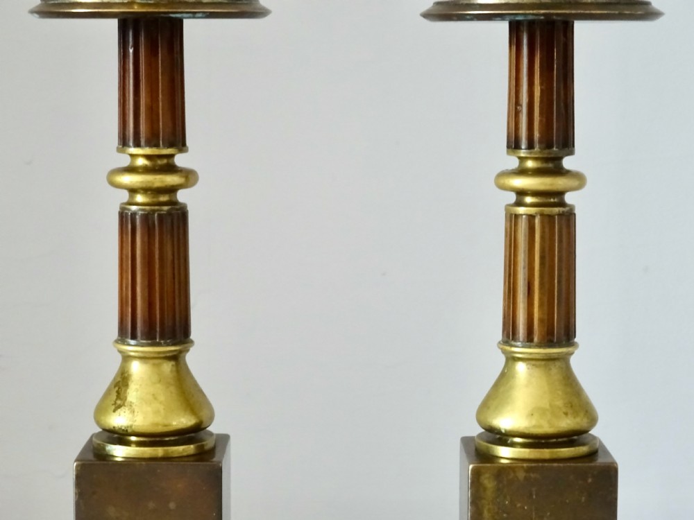 A pair of Edwardian bronze and brass candlesticks featuring fluted shafts, turned sconces, and stepped square bases. View IV