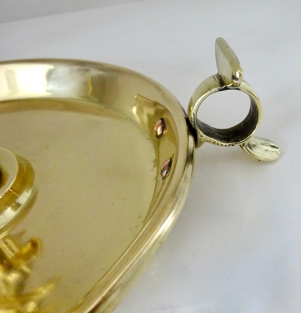 A polished brass candlestick featuring an open spiral twisted stem mounted onto a circular saucer base with a side thumb piece. View IV