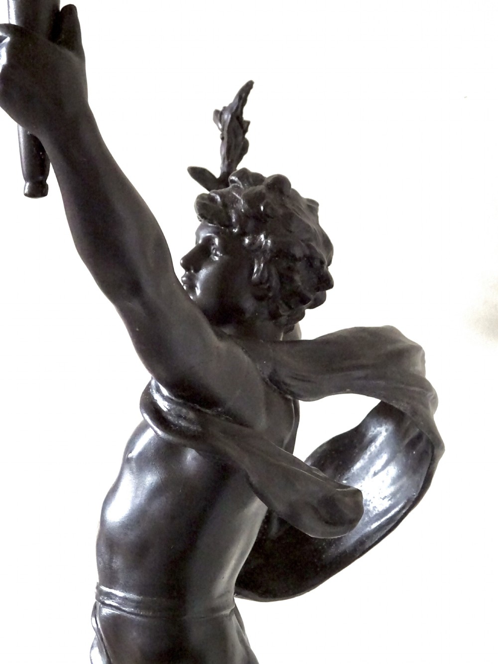 A dark bronze-patinated spelter figure of a classical youth holding a torch light socket on a stepped plinth base. View III