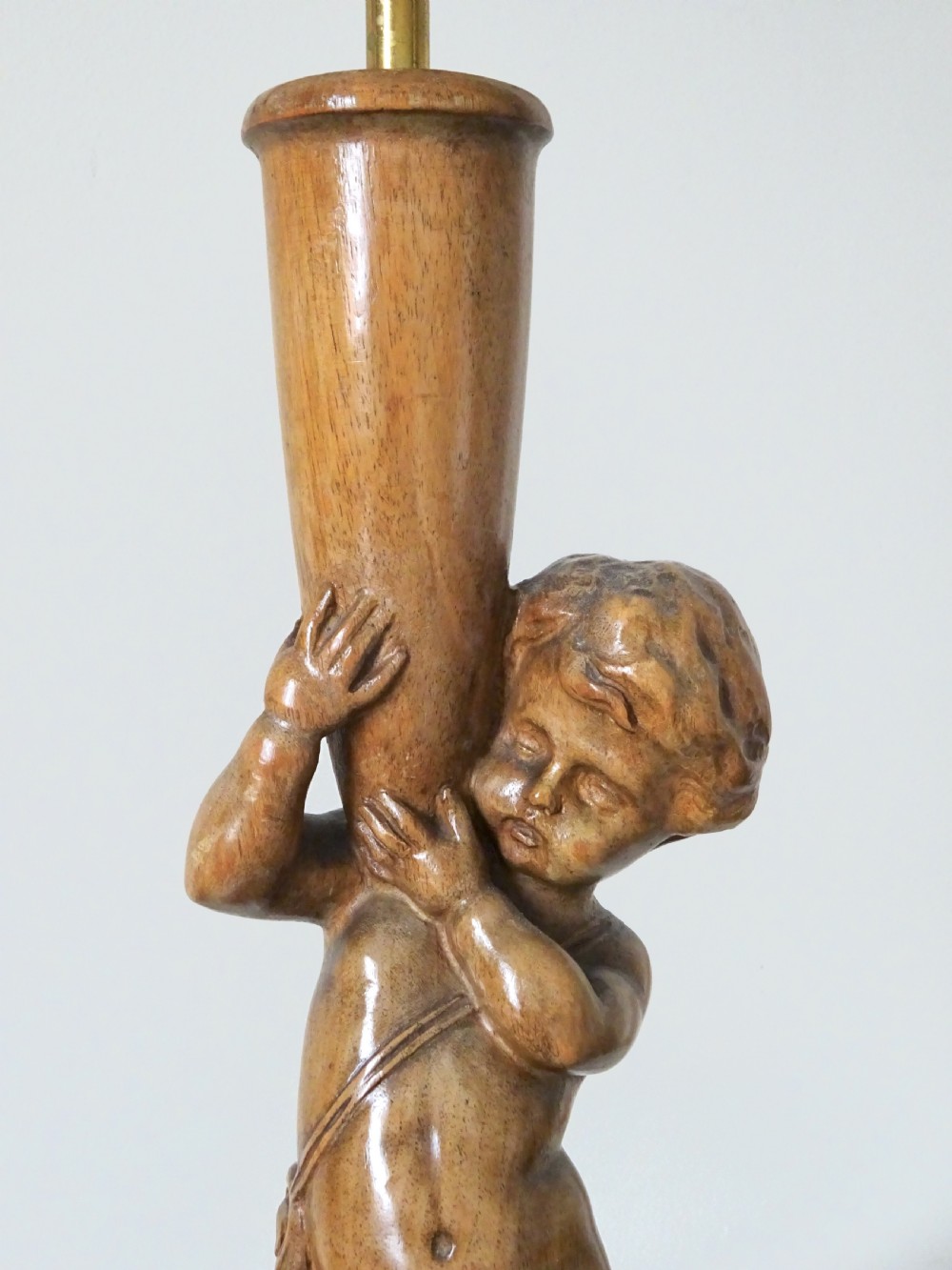 A hand-carved oak table lamp featuring a cherub figure standing on an orb base and holding a fluted stem, topped with a neutral fabric shade. View III