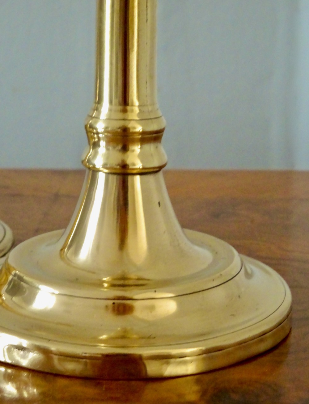 A pair of tall Victorian polished brass candlesticks featuring turned shafts and circular stepped bases. View IV