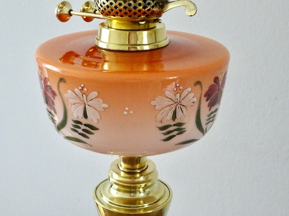 An antique oil lamp featuring a brass pedestal base, a hand-painted floral glass font, and a flared ruffled glass shade. View IV