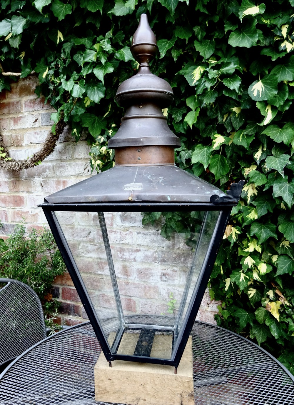 A late Victorian copper street lantern featuring a tiered cap with a finial, clear glass panels tapering downwards, and a black patinated frame.
