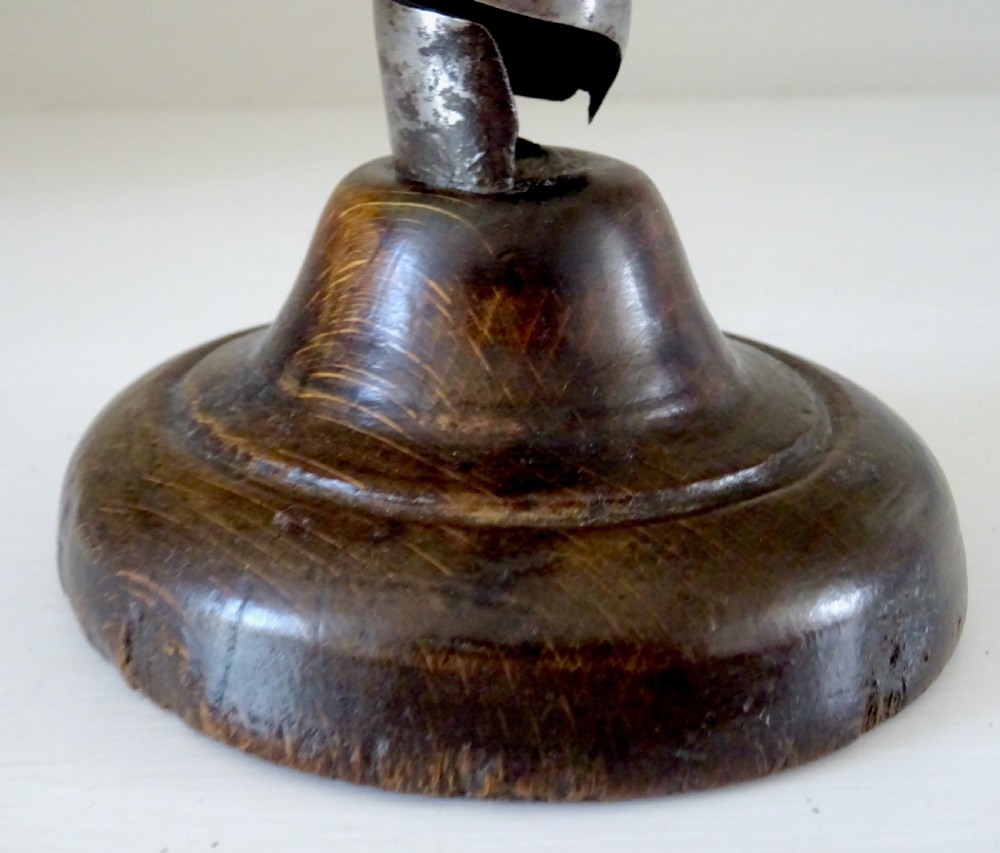 An antique 19th-century iron spiral candlestick with a top hanging hook and internal slider, set into a turned dark wood base. View IV