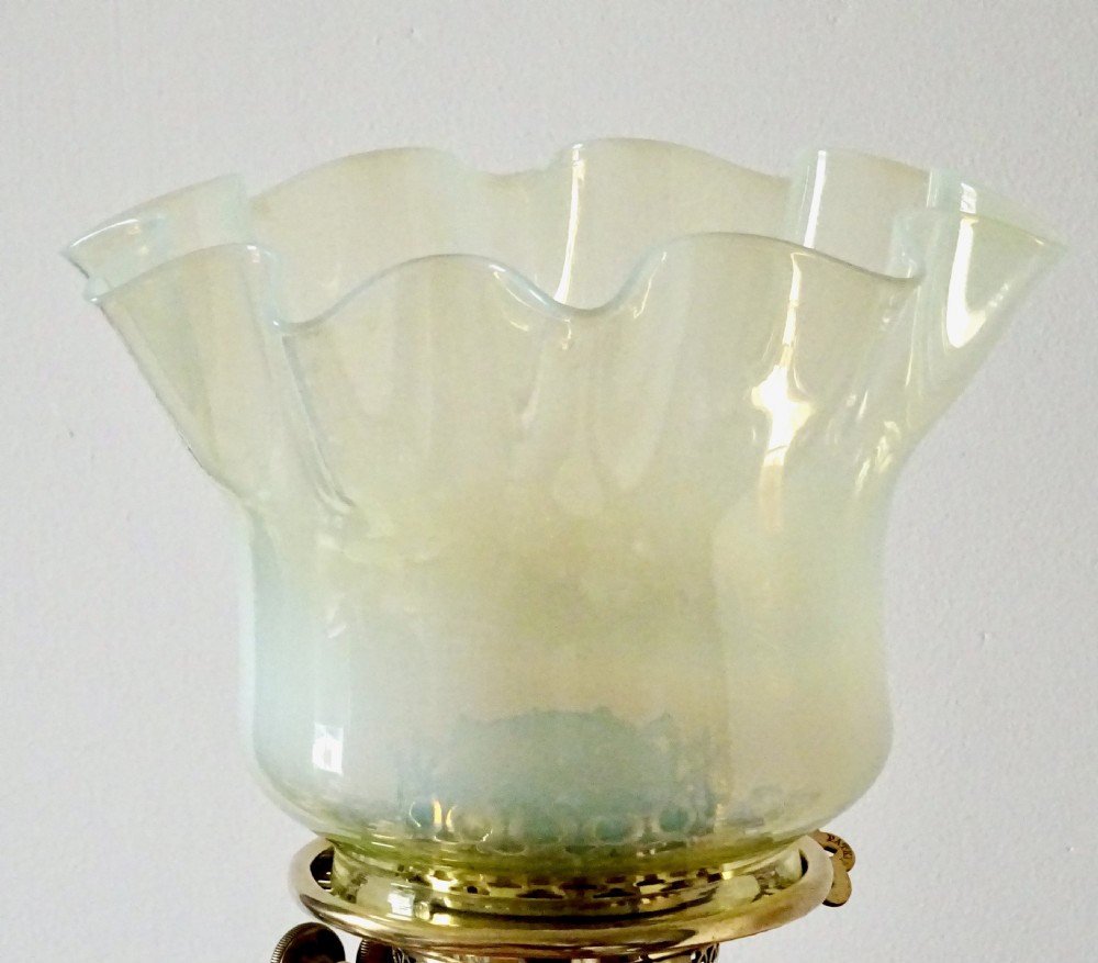 An Arts and Crafts oil lamp featuring a square brass base, a slender turned column stem, a polished copper reservoir, and a pale yellow frilled vaseline glass shade. View VI
