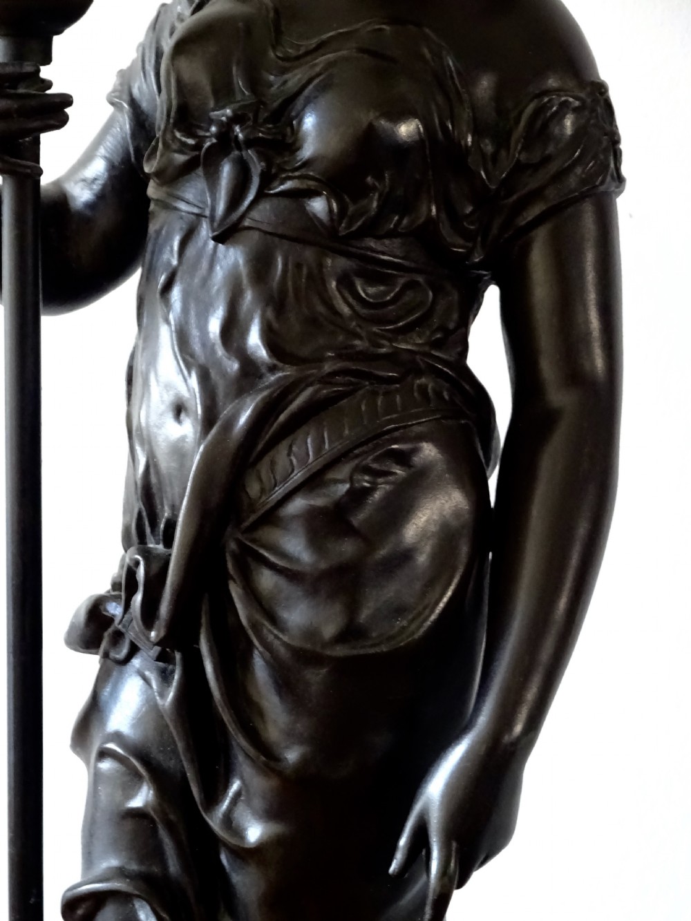 A dark bronze spelter table lamp featuring a classical draped female figure holding a staff topped with a frosted flame glass shade. View IX
