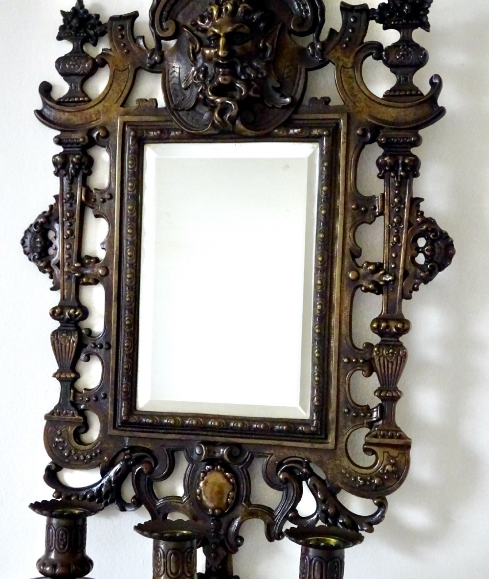 A pair of cast bronze girandole wall sconces featuring rectangular mirrors, three candle branches, and decorative scrollwork frames topped with carved mascaron masks. View V