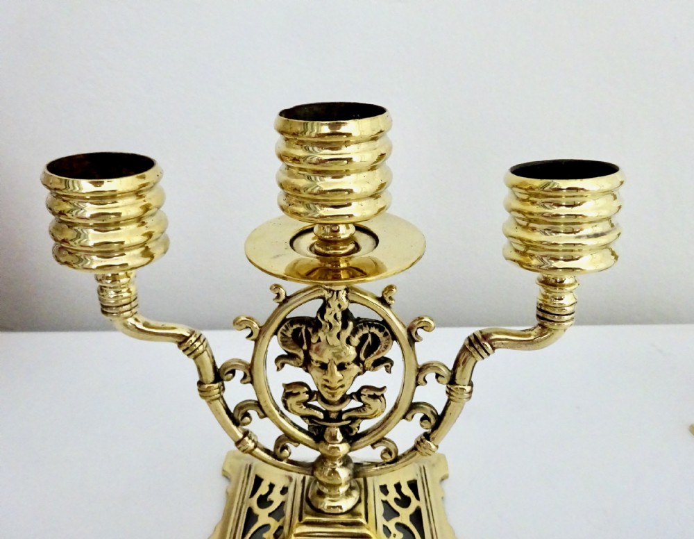 A pair of cast brass three-light candelabras featuring central grotesque mask motifs and pierced square bases. View II