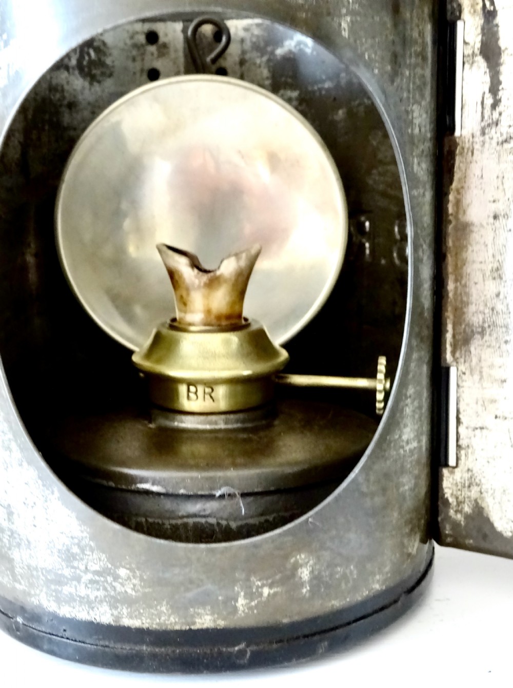 A black painted steel British railway signal oil lamp featuring a brass-rimmed glass lens, carrying handle, and side bracket. View II