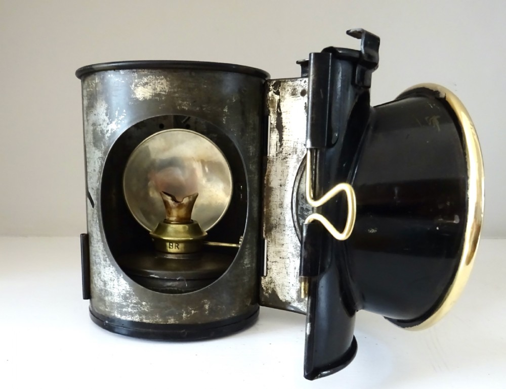 A black painted steel British railway signal oil lamp featuring a brass-rimmed glass lens, carrying handle, and side bracket. View III