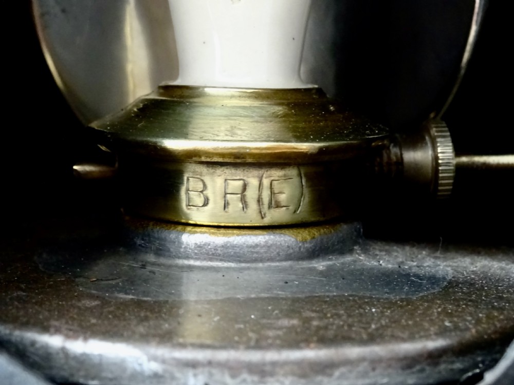 A black painted metal railway oil lantern featuring a hinged glass lens door, carrying handle, and internal brass oil burner. View IV