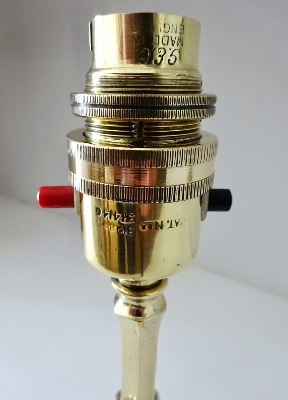 An antique polished brass Pullman table lamp base featuring a turned central stem, a tripod base, and an integral push-button switch. View III