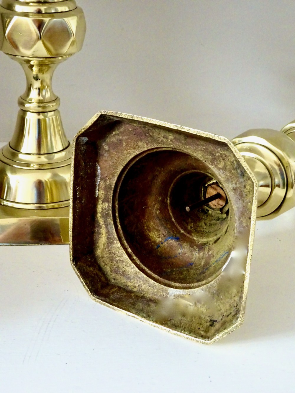 A pair of polished brass Victorian candlesticks featuring faceted knopped stems and square bases. View VI