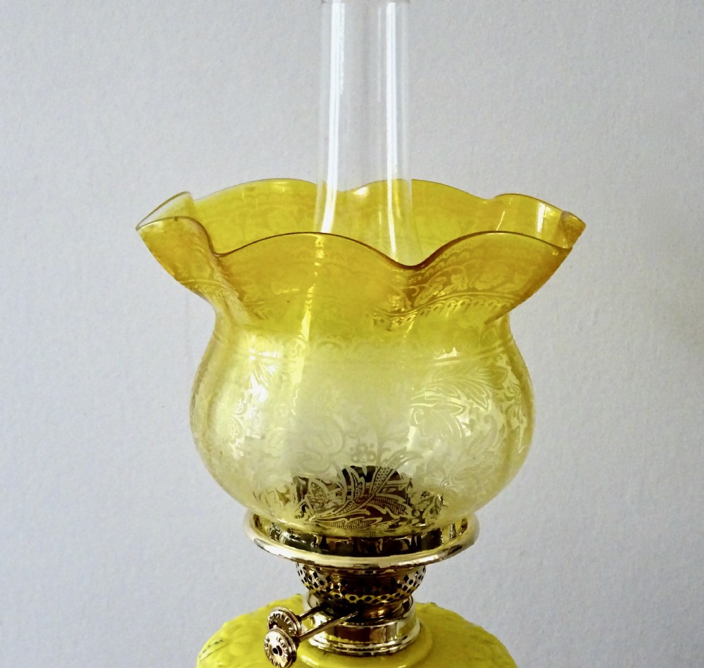A late Victorian oil lamp featuring a yellow glass frilled shade, a moulded yellow glass reservoir, a turned brass pedestal base, and a tall clear glass chimney. View IV
