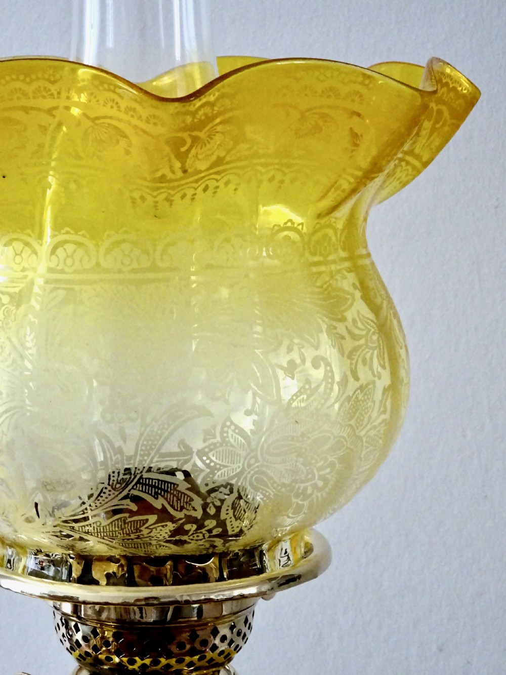 A late Victorian oil lamp featuring a yellow glass frilled shade, a moulded yellow glass reservoir, a turned brass pedestal base, and a tall clear glass chimney. View VII