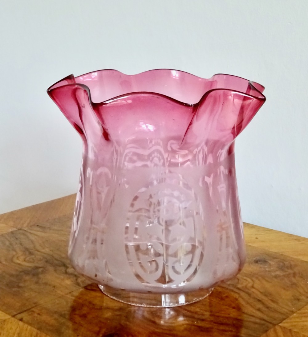 An antique brass column oil lamp with a clear glass reservoir, brass burner, clear glass chimney, and a fluted cranberry glass shade. View VII