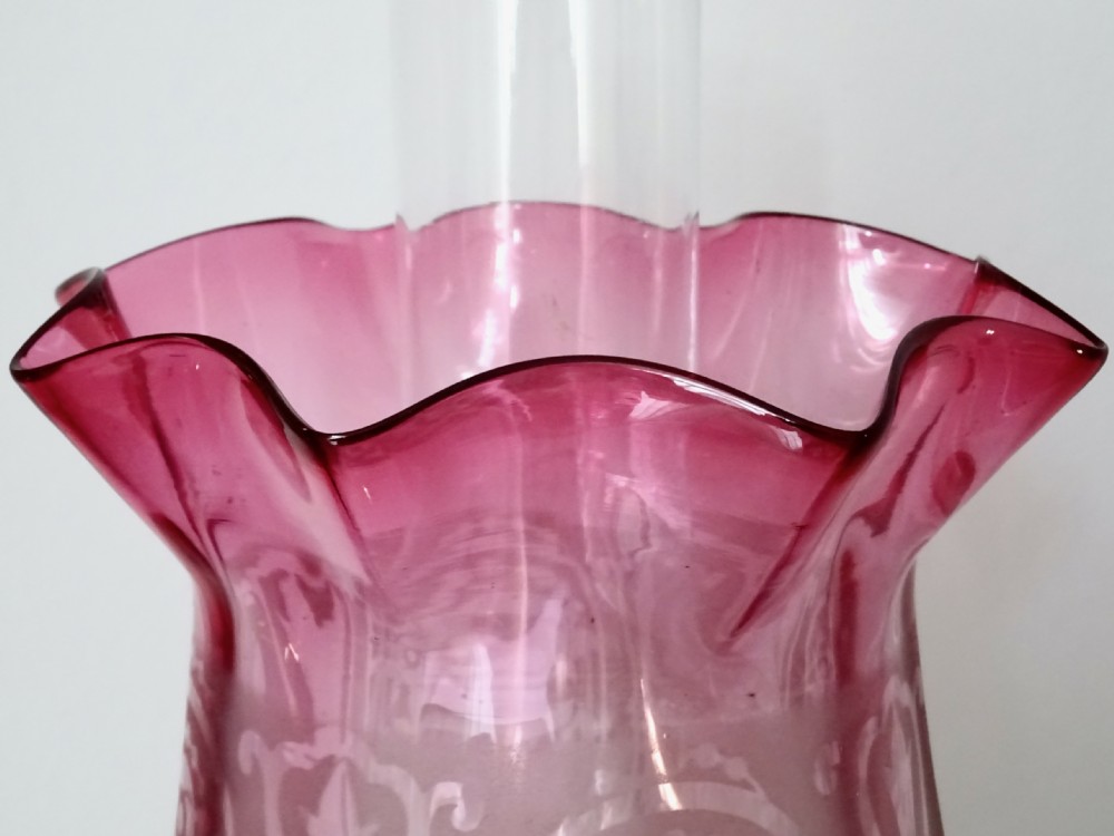 An antique brass column oil lamp with a clear glass reservoir, brass burner, clear glass chimney, and a fluted cranberry glass shade. View VIII