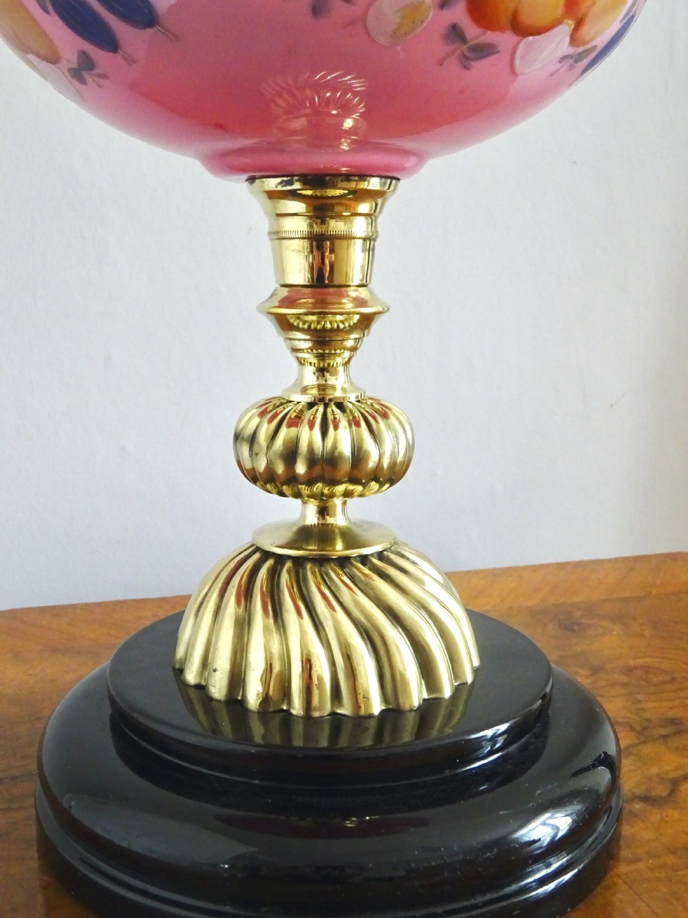 An early twentieth-century brass oil lamp featuring a pink hand-painted glass reservoir, an etched floral glass globe shade, a clear glass chimney, and a black stepped base. View IV