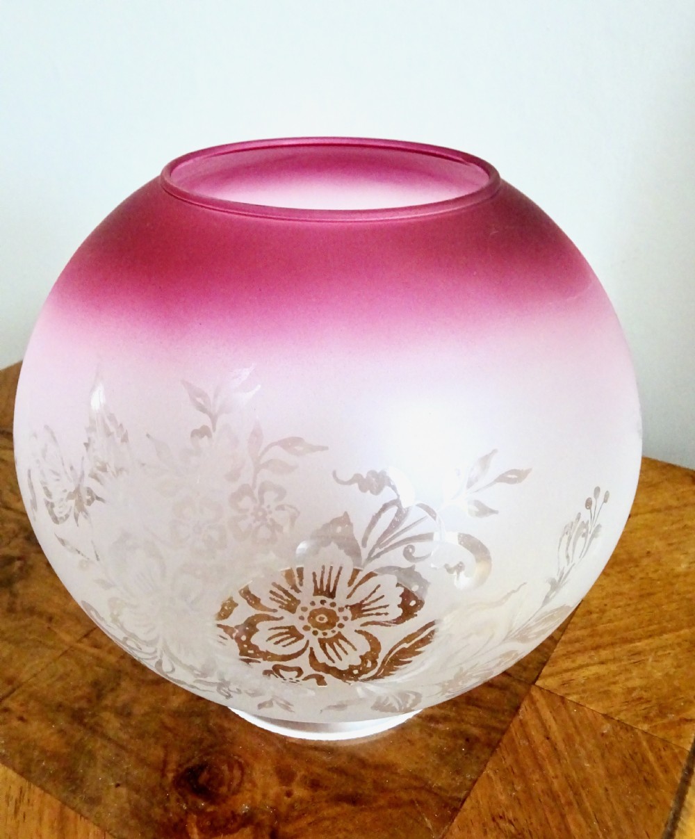 An early twentieth-century brass oil lamp featuring a pink hand-painted glass reservoir, an etched floral glass globe shade, a clear glass chimney, and a black stepped base. View VII