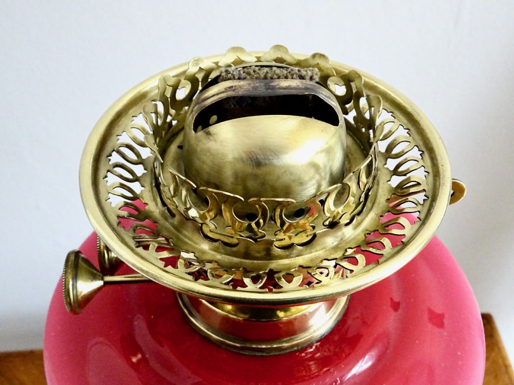 An early twentieth-century brass oil lamp featuring a pink hand-painted glass reservoir, an etched floral glass globe shade, a clear glass chimney, and a black stepped base. View VI