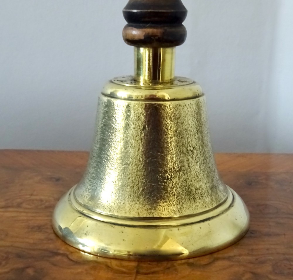 A cast brass hand bell featuring a turned dark wood handle and stamped military markings dated 1942. View III