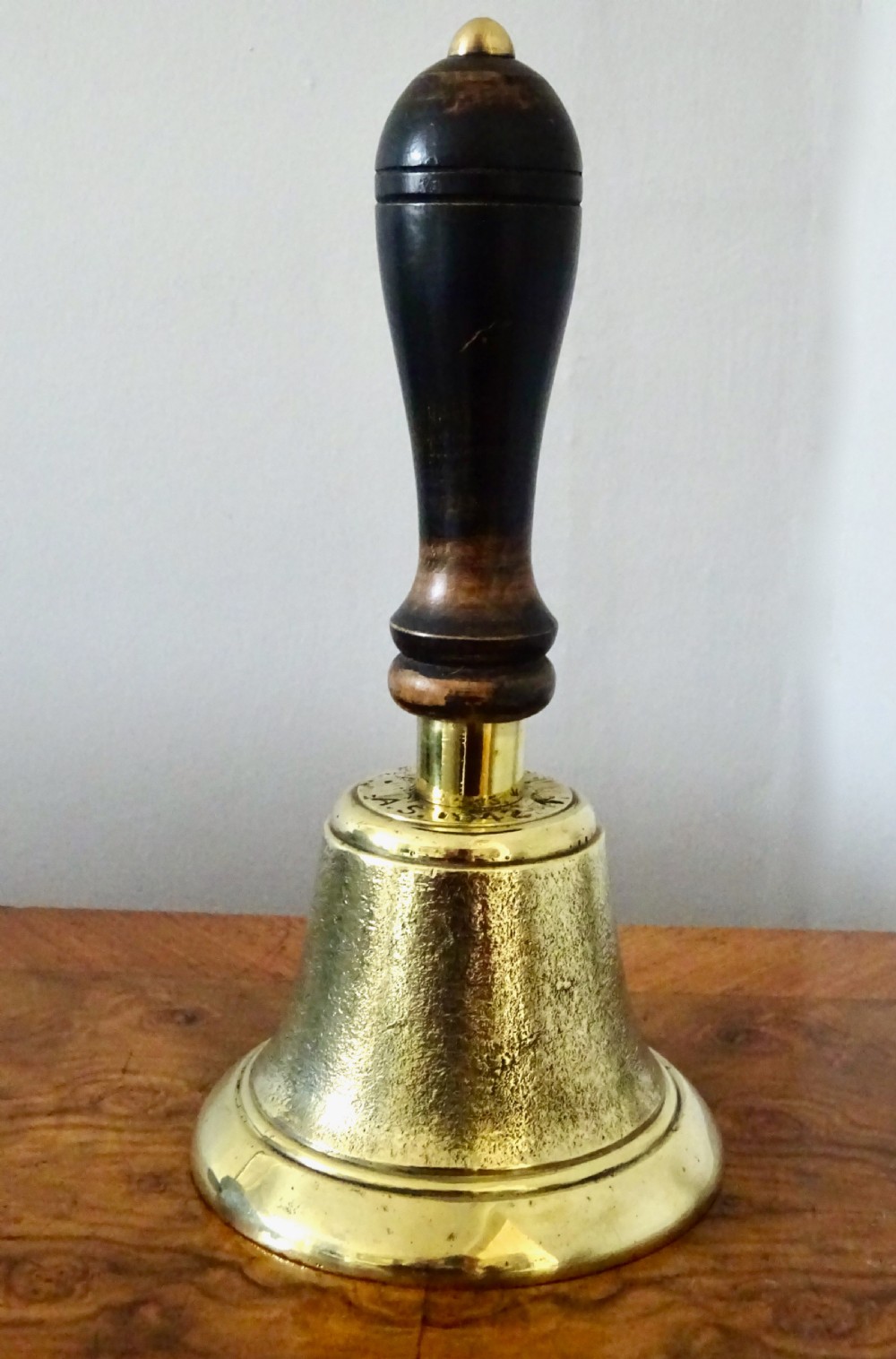 A cast brass hand bell featuring a turned dark wood handle and stamped military markings dated 1942. View VIII